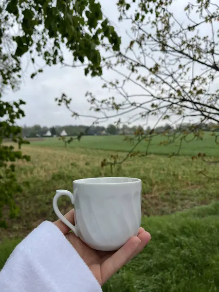 Elinde fincanla yeşil bir bahçenin arka planında