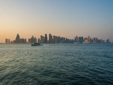 Bir tekne ve Doha şehri gün batımında gökyüzüne yükseliyor, Doha, Katar