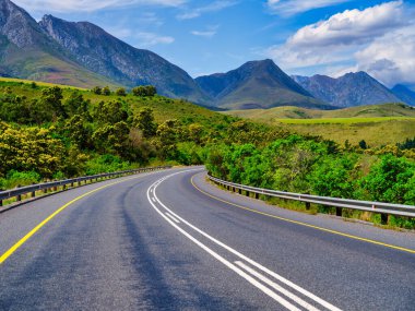 Arka planda Langeberg Dağları, Batı Burnu, Güney Afrika 'daki Swellendam kırsalından dolambaçlı yol