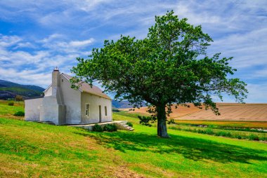 Caledon, Overberg, Batı Burnu, Güney Afrika 'da mavi gökyüzü ve beyaz bulutlu bir çiftlik evi.