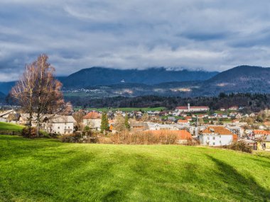 Kamnik köy evleri, yemyeşil çayır ve dağ bulutlu bir öğleden sonra, Kamnik, Slovenya