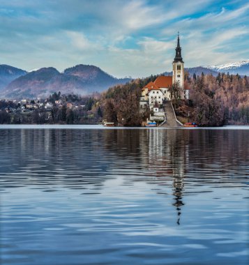 Slovenya 'nın Bled Gölü' nün kuzeyindeki kilisenin panorama görüntüsü ve soldaki köyün kanaması bulutlu bir kış öğleden sonrasında çekildi.