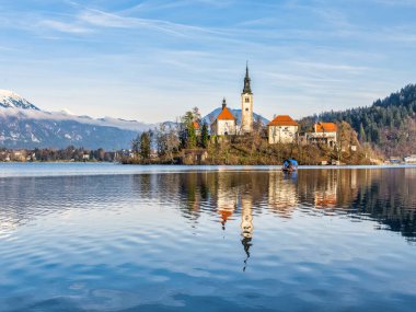 Bled Adası Kilisesi ve kar zirvesi dağlarının alçak açılı görüntüsü, Slovenya, Bled 'de bir kış öğleden sonra