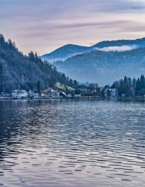 Slovenya 'da kışın göl kıyısında köy ve dağ kanadı.