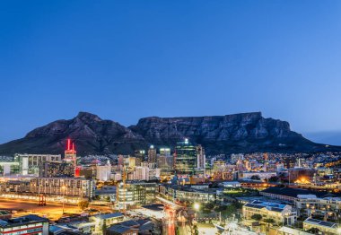 Cape Town 'daki binaların ve sokakların geniş açılı görüntüsü arka plandaki masa dağıyla geceleyin aydınlandı. Cape Town, Güney Afrika