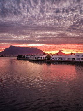 Woodbridge Adası 'nın dikey çekimi ve arka plandaki masa dağının dramatik günbatımı, Cape Town, Güney Afrika
