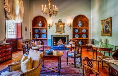 Antika mobilyalar ve çömleklerle şömineli klasik oda dekoru.