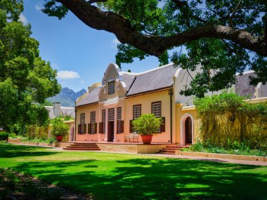 Vergelegen Şarap Malikanesi, Somerset Batı, Güney Afrika 'da yemyeşil bahçe ve ağaçlarla çevrili Hollanda Burnu binaları