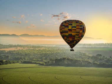 Magaliesburg vadisindeki yemyeşil tarlalarda uçan renkli sıcak hava balonu, Gauteng, Güney Afrika