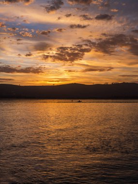 Knysna lagününün üzerinde dramatik gökyüzü bulutlarıyla altın günbatımının portresi Güney Afrika