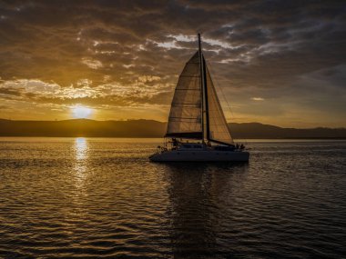 Manzara, su yüzeyine yansıyan altın bir günbatımını ve Knysna lagün bahçesi rotasından geçen bir yelkenliyi vurdu.