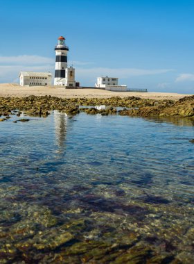 Portrait water level shot of Cape Recife Lighthouse on a clear day with reflection clipart