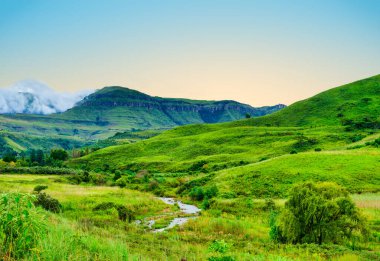 Drakensberg, KwaZulu-Natal, Güney Afrika 'da kayan tepeler ve dağlarla dolu gür bir vadi.
