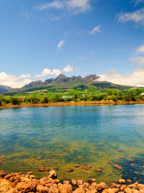 Kristal berraklığında bir su barajının dikey görüntüsü ve Helderberg Dağı yamaçlarında üzüm bağları, Somerset West, Güney Afrika