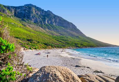 Gün batımında Sandy Körfezi Sahili 'nin dingin güzelliğini gösteren geniş açılı bir çekim. Cape Town, Güney Afrika' daki okyanus ve gökyüzüne canlı renkler yansıyor..