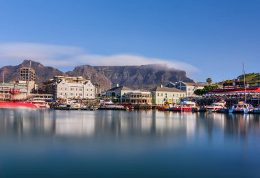 Yakın çekim, V ve A Waterfront 'un ışıklarını yakalar, bulutlar Masa Dağı' nın üzerinden geçerken hareket bulanıklığı yaratır. Cape Town, Güney Afrika
