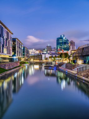 Çarpıcı bir dikey uzun pozlama V ve A Waterfront ve Cape Town şehrinin canlı ışıklarını yakalar ve günbatımından sonra pürüzsüz kanala güzel yansıtır.