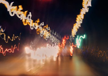 Bulanık şehir gece lambaları ve araba farları uzun pozlarda iz bırakıyor.