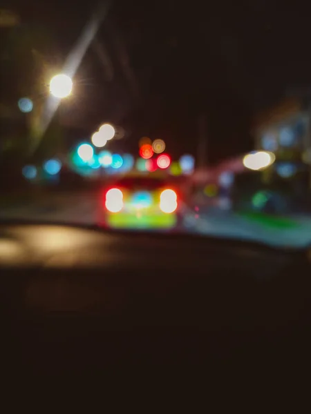 从车里看到一条有车和防波堤灯的街道的模糊图像 — 图库照片