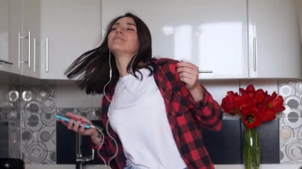 Ευτυχισμένη Νεαρή Γυναίκα Χορεύει Στην Κουζίνα Ακούγοντας Μουσική Στο Smartphone — Αρχείο Βίντεο