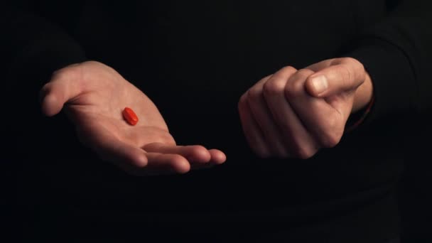 スタジオで撮影された男性の手は黒の背景に隔離された赤い錠剤を示しています 正しい選択をするという概念 シネマティック4K映像 — ストック動画