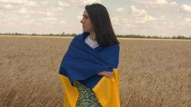 Ukraynalı vatansever kadın portresi Ukrayna 'nın mavi-sarı bayrağıyla bir buğday tarlasında duruyor.