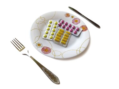 Sarı ve pembe haplar tabak çatal bıçak seti konseptinde su topluyor.