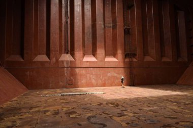 onboard ship, at sea - january 8, 2023 : crew member scrapping tank top inside an empty cargo hold of a bulk carrier ship