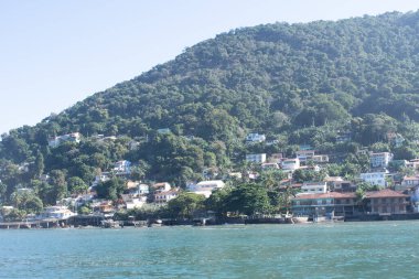 Deniz kıyısındaki dağ yamacında insan yaşam alanı olan manzaralı bir ada.