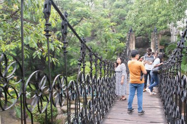 Rock Garden, Ranchi, Jharkhand, Hindistan - 14 Temmuz 2024: İnsanlar klasik görünümlü dekore edilmiş ayak köprüsünde gezinmenin keyfini çıkarıyorlar