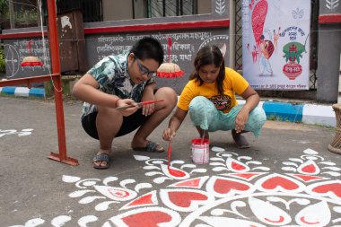 khanpur, kolkata, batı bengal, Hindistan-Ekim 2024: Durga puja olayında yolun kültürel güzelleşmesini artırmak için sokaklara renkli Rangoli resimleri çizen çocuklar