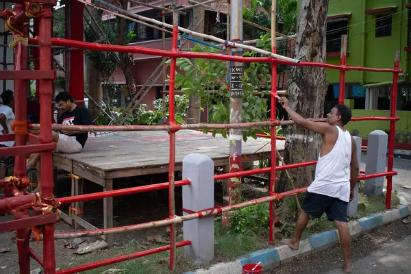 khanpur, kolkata, batı bengal, Hindistan-Eylül 29, 2024: Durga puja festivali için pavyon dikmek için kullanılan bambu yapının üzerine bir dekorasyon sanatçısı