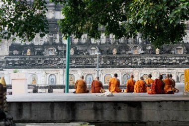 mahabodhi tapınağı, bodh gaya, bihar, Hindistan - 22 Eylül 2024: Budist rahipler geleneksel yollarla dua ediyor ve meditasyon yapıyorlar. Tapınaktaki ağaç yaprağının altında yapayalnız bir şekilde oturuyorlar.