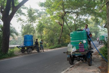 Jagulgachi, Erenda, Batı Bengal, Hindistan - Kasım 03, 2024: Motorlu araçlar yol kenarındaki tesislerden içme suyu yüklüyorlar.