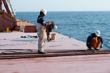 Hint Okyanusu, Güney Afrika kıyıları, gemi-Haziran 06, 2025: Kargo ambarının kapağını kapatan gemi mürettebatı rampa bantlı duba delikleri.