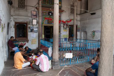 Hanseshwari Tapınağı, Bansberia, Batı Bengal, Hindistan - 23 Temmuz 2025: fanatikler çiçek ve adaklarla bir Hindu ayini düzenlemek için geleneksel tapınak içinde toplanırlar, canlı duvar sanatının iç kısımları, çerçeveli portreler ve el yazıları