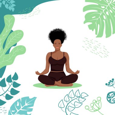 A beautiful African American girl sits in the lotus position among tropical leaves. A healthy way of life.