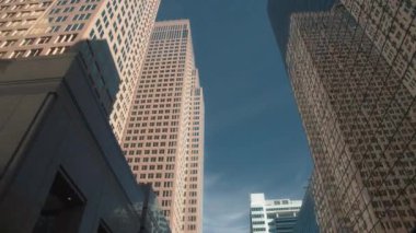 Şehir merkezindeki finans bölgesinde yansıtıcı cepheli yüksek binalar. Yavaş çekim, düşük açı görüş, doli çekim. 