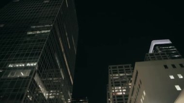 Geceleri şehir merkezindeki yansıtıcı ofis binasının önünden geçiyor. Yavaş çekim, düşük açı görüş, doli çekim. 