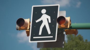 Önden geçen yayalar mavi gökyüzü arka planında yanıp sönen trafik ışıklarını uyarıyorlar. 