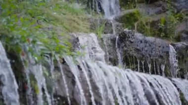 Güzel çağlayan şelale dağ kayalarının arasına düşüyor. Yavaş çekim. 
