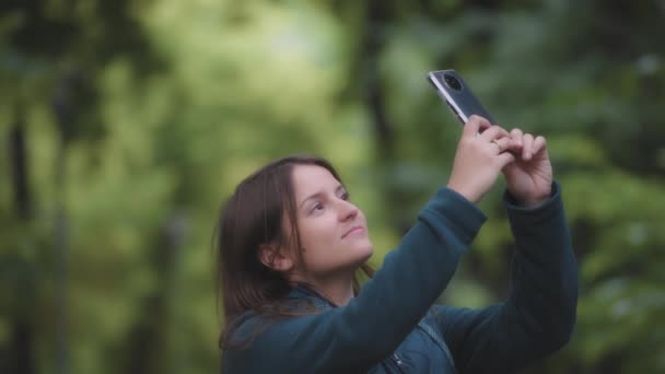 Uma Jovem Mulher Tirando Fotos Das Árvores Com Telefone Desfocado — Vídeo de Stock