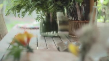 Çiçekler ve bitkilerle süslenmiş ahşap bir masada servis edilen güzel yemek aperatifleri. Yavaş çekim, yüzeysel alan derinliği.