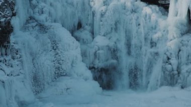 Neredeyse donmuş şelalede su ve buz. Kış manzarası. Yavaş çekim. 