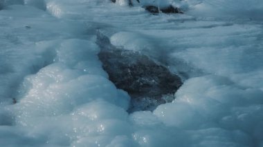 Dağ suyu kışın buzun içinden akar. Yavaş çekim. 