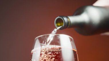 Close up of rose wine being poured from the bottle into a wineglass. Slow motion. 