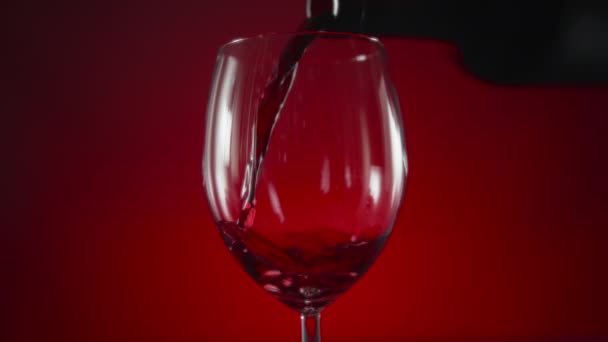 Kırmızı Arka Planda Şarap Bardağına Dökülen Kırmızı Şaraba Yakın Çekim — Stok video