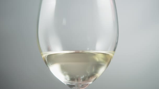 Beyaz Şarabı Gri Arka Planda Bir Bardağın Içinde Kapat Yavaş — Stok video