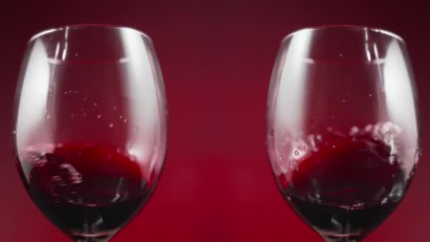 Two Wine Glasses Shaking Swirling Red Wine Red Background Slow — Videoclip de stoc
