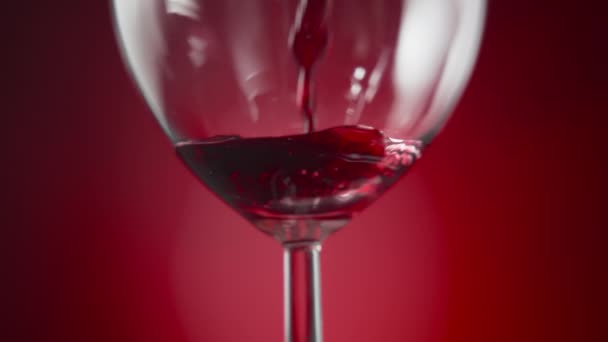 Kırmızı Arka Planda Şarap Bardağına Kırmızı Şarap Dökmeye Yakın Yavaş — Stok video